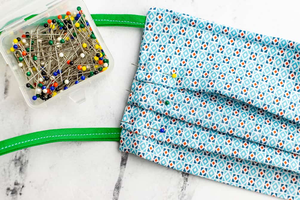 use pins to secure three pleats on a fabric surgical mask