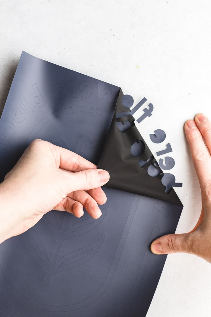 overhead view of using fingers to pull back the excess vinyl from the carrier sheet