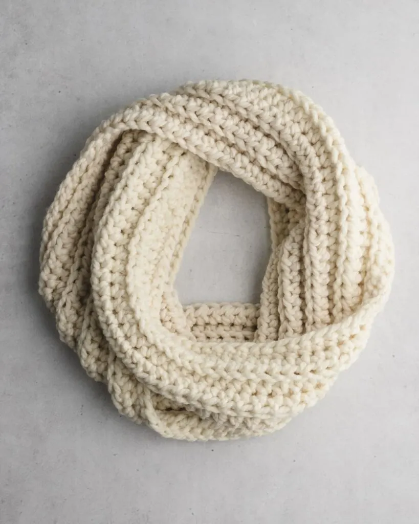 cream colored crochet scarf made with bulky yarn on a gray background