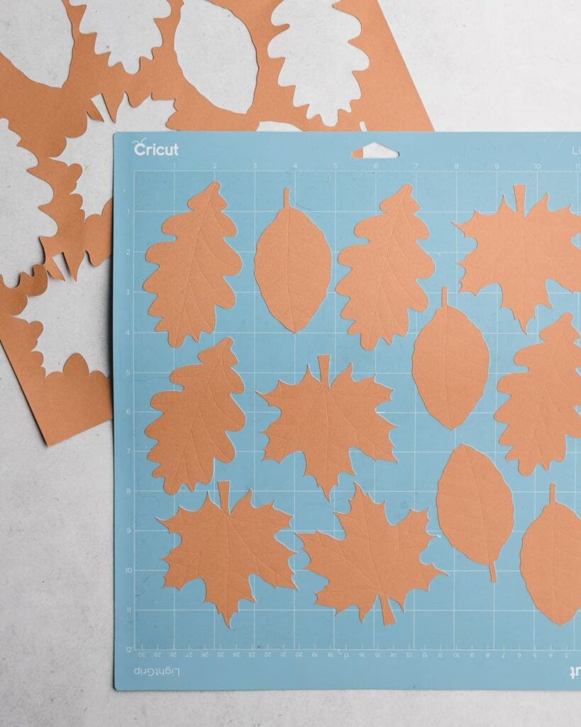 cut kraft paper leaves on a light blue Cricut cutting mat