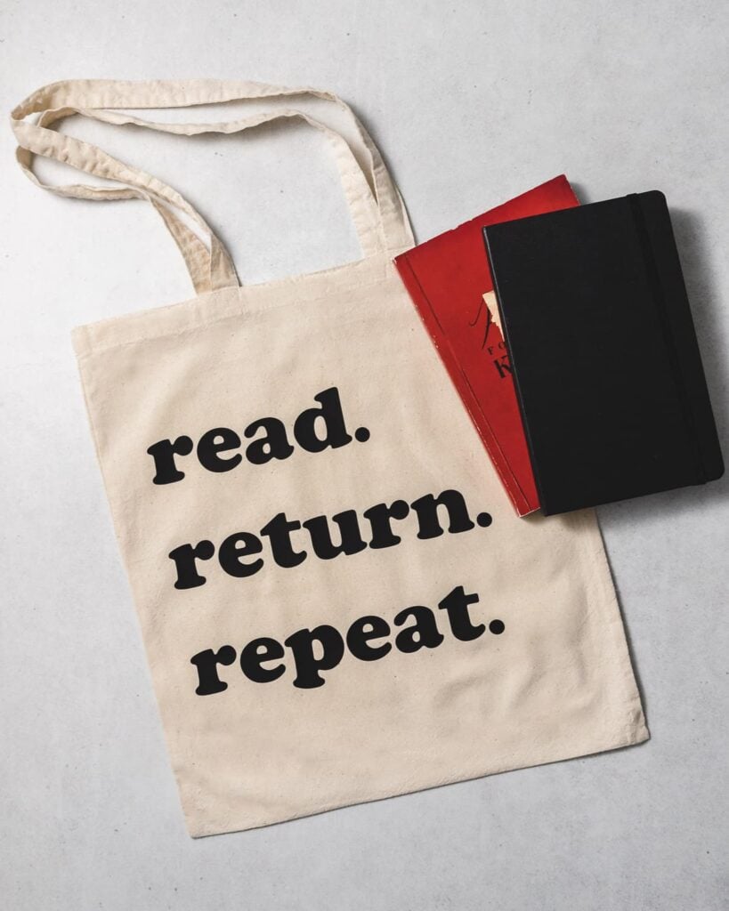 finsihed library tote bag with the words read return repeat in black iron-on vinyl