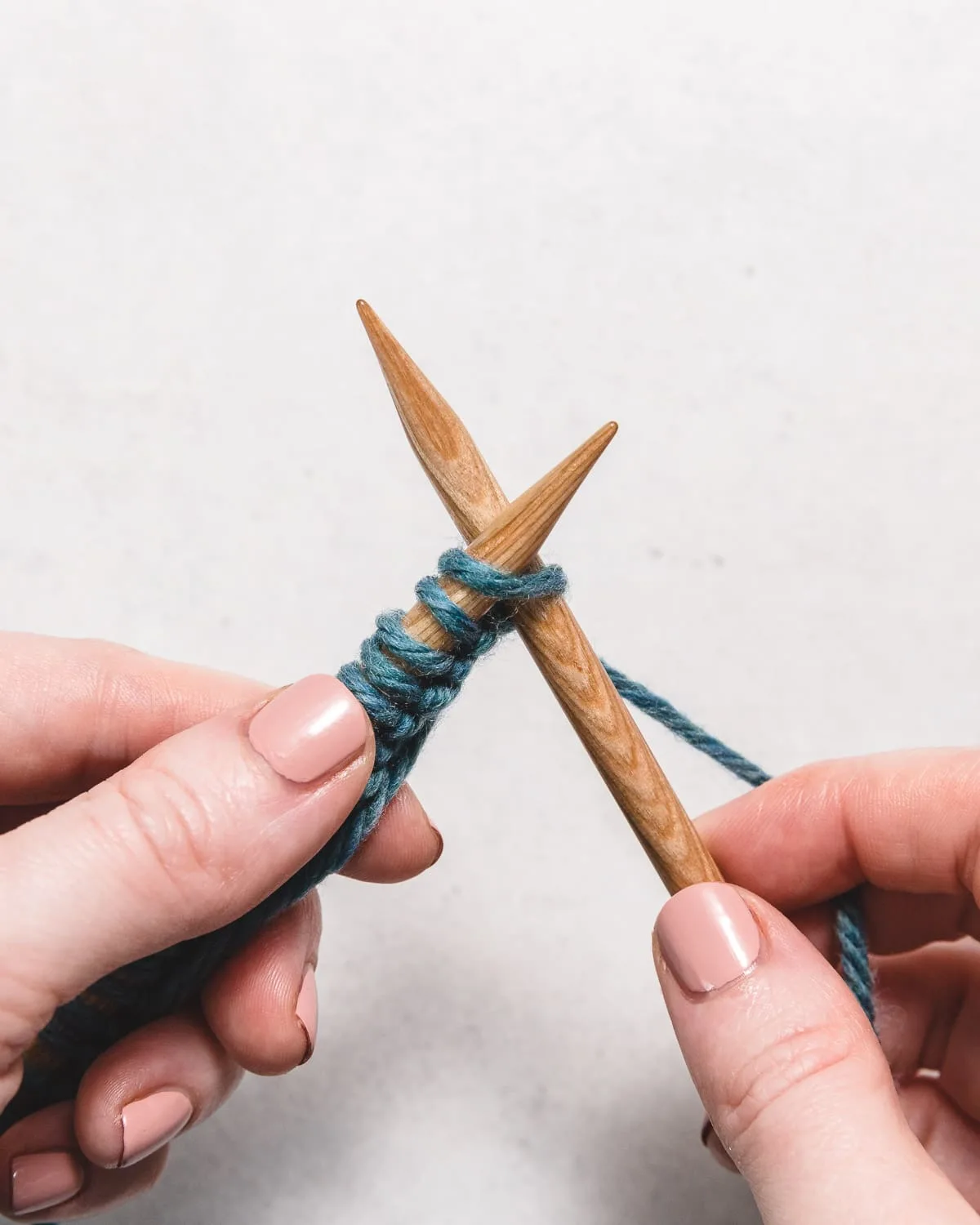 two knitting needles and blue yarn showing how to start the knit stitch