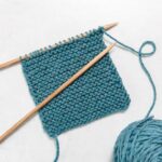 a garter stitch swatch on the needles on a gray background