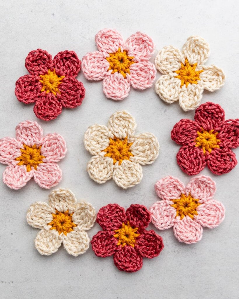 9 pink crochet flowers on a gray background