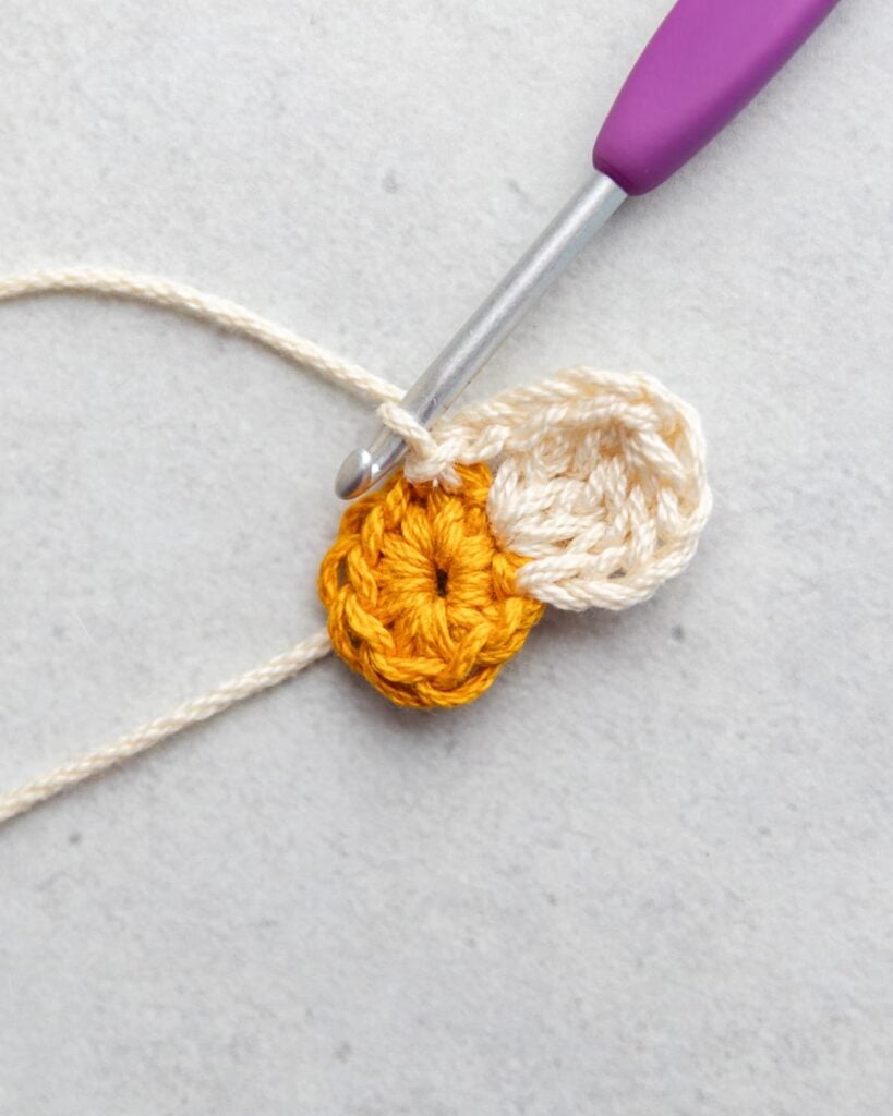 attaching a petal with a purple crochet hook on a gray background